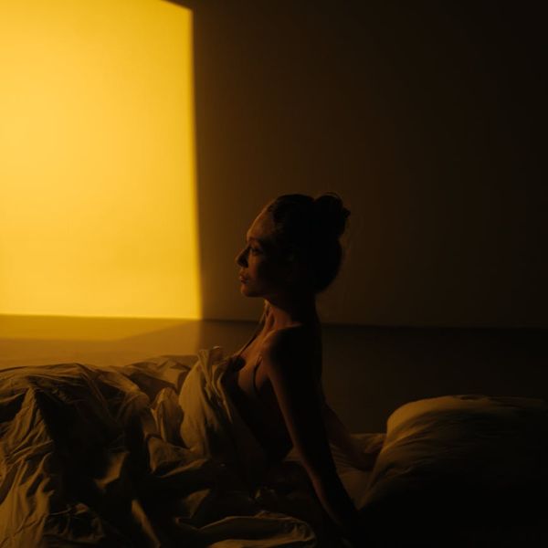 Person meditating peacefully with soft purple lighting.