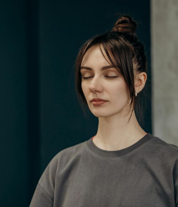 Woman in a calm yoga pose in a minimalist dark room.